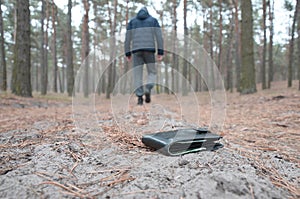 Young man loses his purse with euro money bills on Russian autumn fir wood path. Carelessness and losing wallet concept