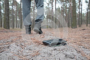 Young man loses his purse with euro money bills on Russian autumn fir wood path. Carelessness and losing wallet concept