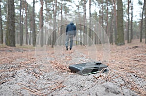 Young man loses his purse with euro money bills on Russian autumn fir wood path. Carelessness and losing wallet concept