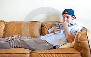 Young man lounging on the couch using social media