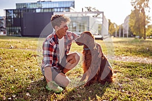 The young man loves to spend time with his dog in the park. Friendship, walk, pets