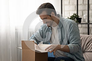 Young man loyal client of postal service unboxing small package