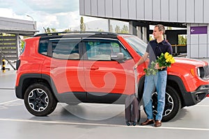 A young man with luggage stands near a car. Business trip, vacation concept