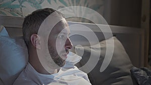 Young man lying in the bed with laptop before sleeping