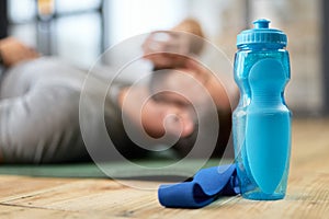 Young man lying on the floor with bottle of water and fitness band