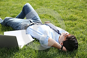 Young man lying on green lawn in park