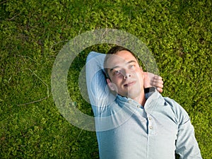 Young man lying on green moss