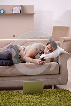 Young man lying on the sofa at home