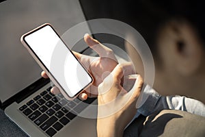 Young man lying on sofa with laptop computer and using smart phone.