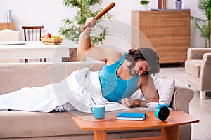 Young man lying on the sofa in time management concept