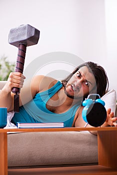 Young man lying on the sofa in time management concept