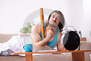 Young man lying on the sofa in time management concept