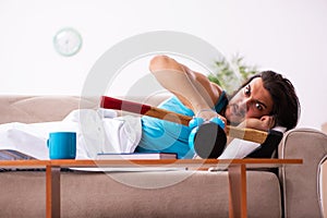 Young man lying on the sofa in time management concept