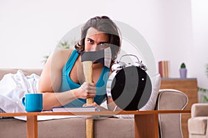 Young man lying on the sofa in time management concept