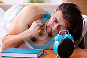 Young man lying on the sofa in time management concept