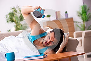 Young man lying on the sofa in time management concept