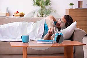 Young man lying on the sofa in time management concept