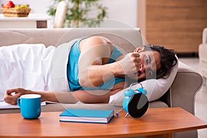 Young man lying on the sofa in time management concept