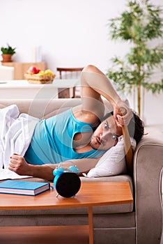 Young man lying on the sofa in time management concept