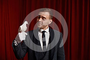 Young man magician showing trick with white dove bird selective focus