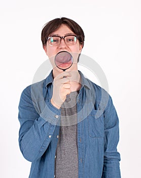 Young man with magnifying glass on grey background. Curious young man with magnifying glass Isolated on grey background