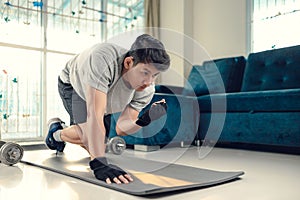 Young man making abdominal exercises on yoga mat in living room at home. Fitness, workout and traning at home concept