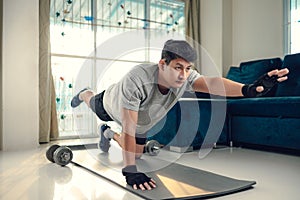 Young man making abdominal exercises on yoga mat in living room at home. Fitness, workout and traning at home concept