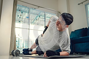 Young man making abdominal exercises on yoga mat in living room at home. Fitness, workout and traning at home concept