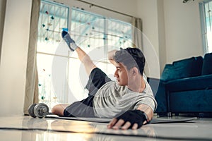 Young man making abdominal exercises on yoga mat in living room at home. Fitness, workout and traning at home concept