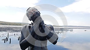 Young Man Making Face Mask with Black Medical Mud at the Lake of Salt Water. Salty Black Dirt Is Good For People With