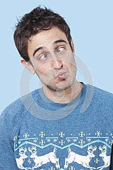 Young man making funny faces over blue background