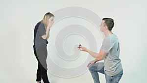 Young man making marriage proposal to his girlfriend. Man is kneeling to the young woman proposing to the girl to get