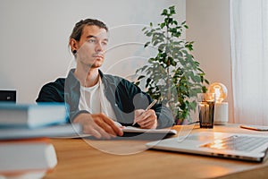 Young man making notes while online learning