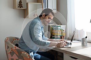 Young man making notes from online tutorial on distant learning