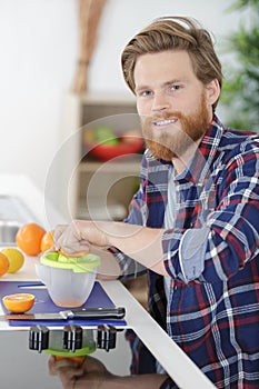 young man making orange juice in kitchen