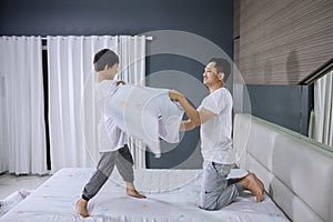 Young man making pillow fight with his son