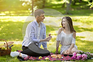 Young man making proposal to his girlfriend, giving her engagement ring at park