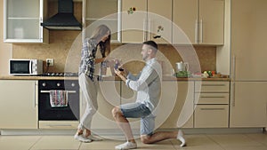 Young man making proposal to his girlfriend in the kitchen at home