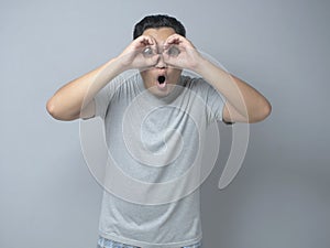 Young Man Making Telescope Gesture With His Hand, Shocked Expression