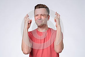 Young man making a wish crossing fingers isolated on white background