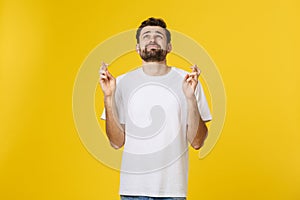 Young man making a wish isolated on yellow background