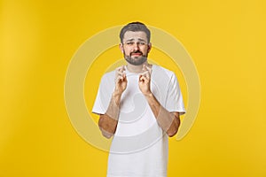 Young man making a wish isolated on yellow background