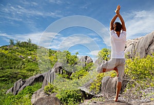 Young man making yoga tree pose outdoors