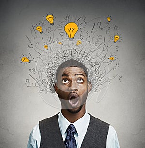 Young man with many idea light bulbs above head looking up