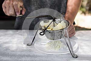 Young man mashing boiled potatoes