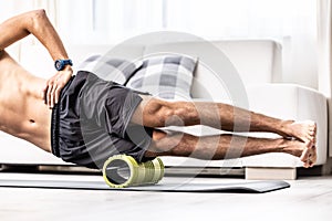 Young man massage lateral thigh muscle with foam roller