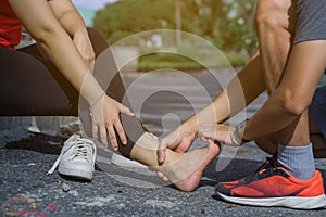 Young man massaging young woman on painful ankle. Suffering from ankle injury while exercising and running . Sport and exercise