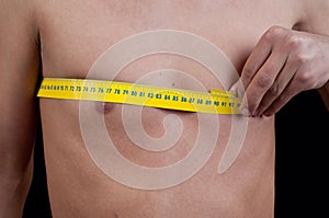 Young man measuring his chest