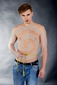 Young man measuring waist.