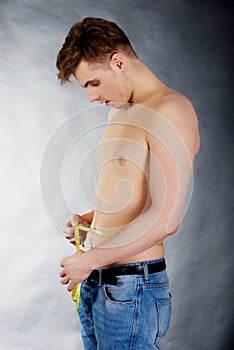 Young man measuring waist.